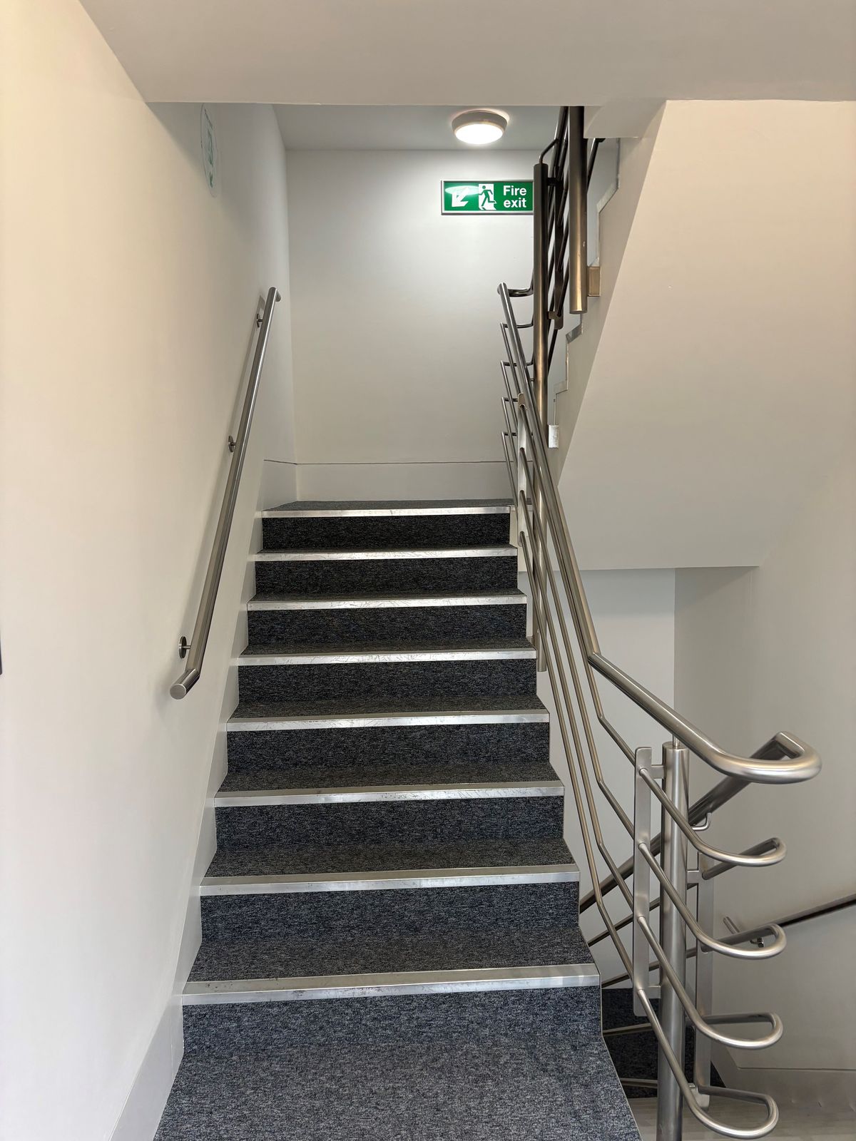 Freshly decorated commercial stairwell with stainless handrails by DPK Carpentry & Decorating