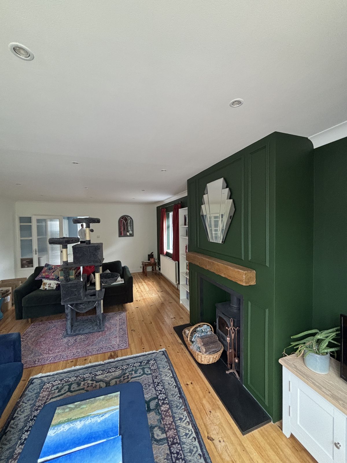 Dark green panelled feature wall with oak mantel and log burner — carpentry and decorating by DPK